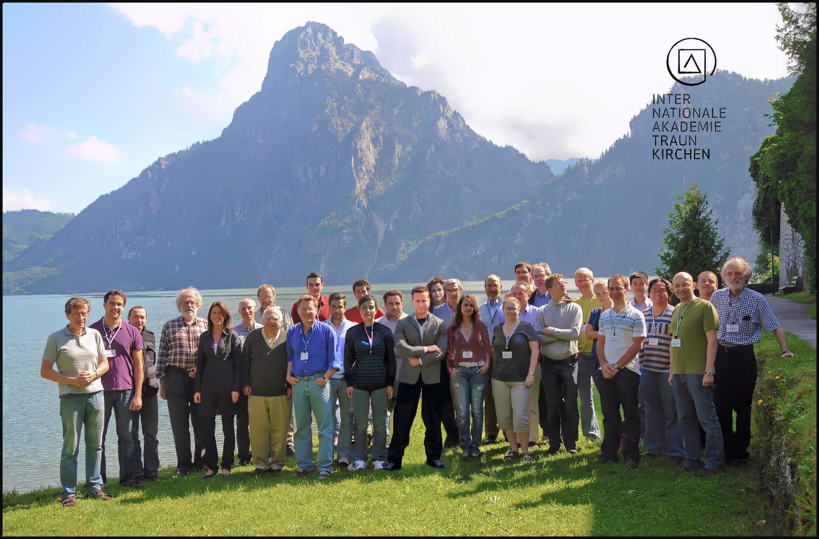 Group photograph of workshop participants standing on a lawn beside Lake Traunsee, with the Traunstein mountain rising behind them.